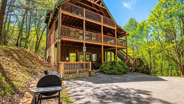 A two-story log cabin with a balcony, surrounded by trees. - Hilltop Bearadise (Gatlinburg)