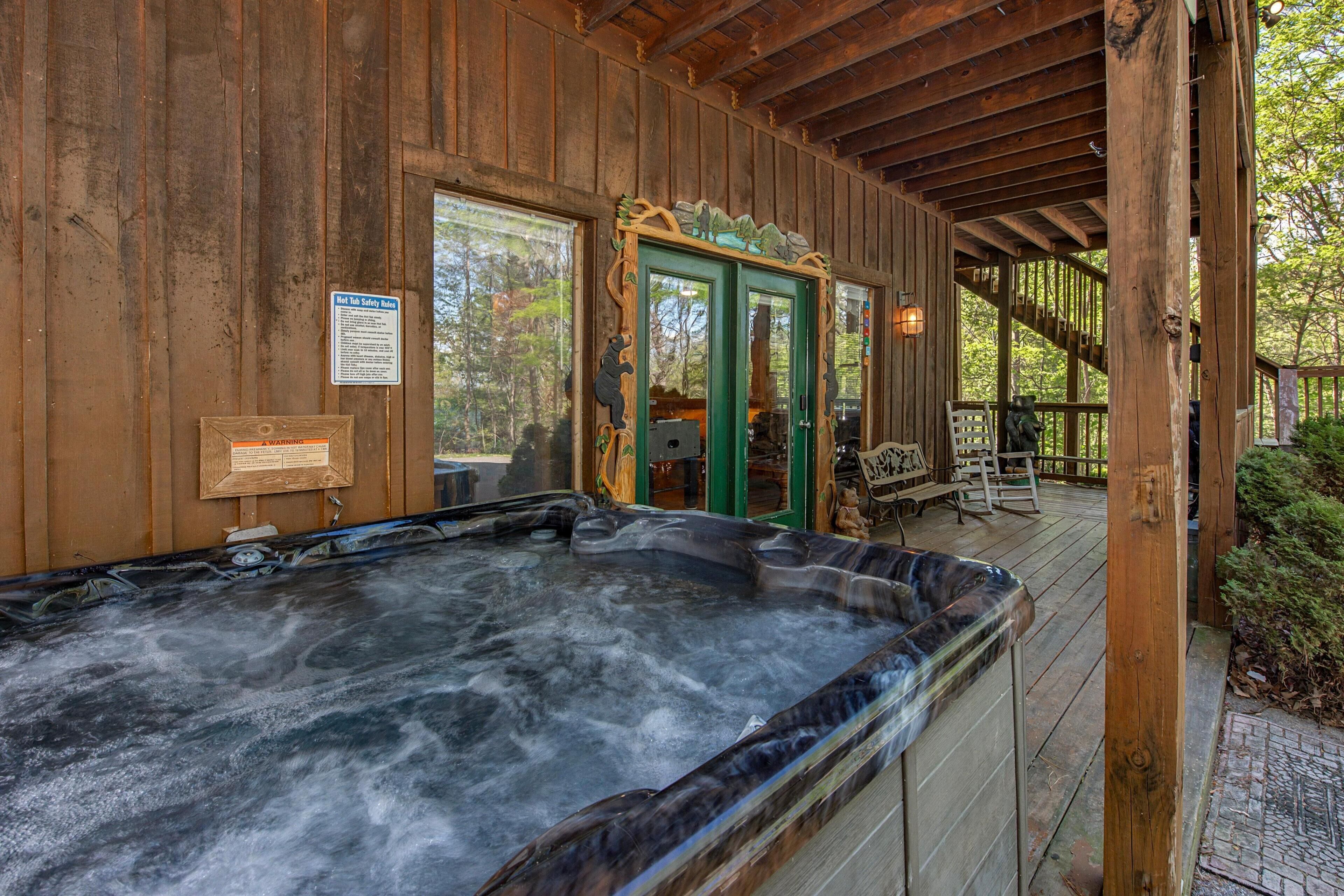 A wooden cabin with a hot tub, wooden deck, and a green door.