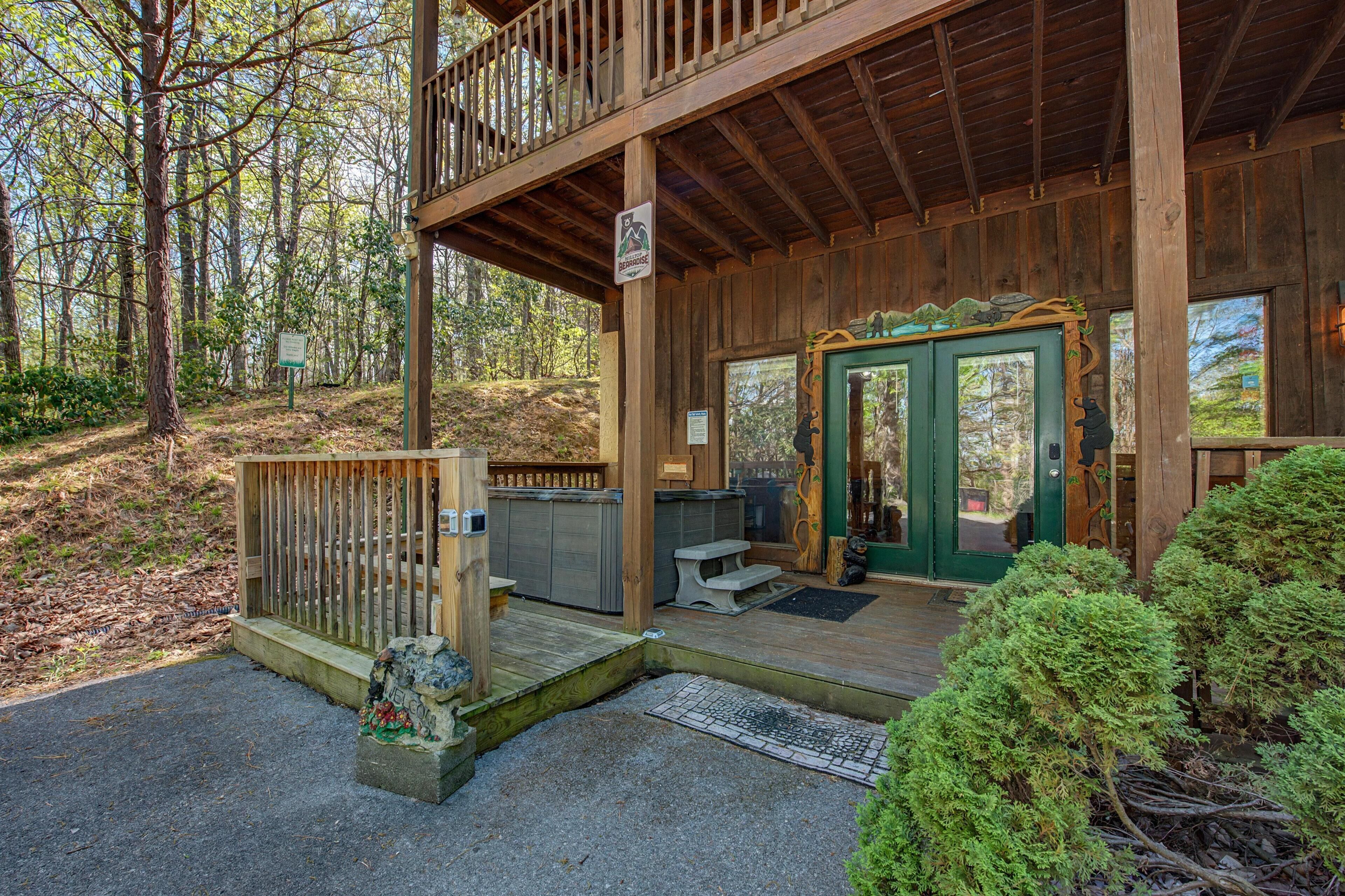 A wooden cabin with a porch, a covered deck, and a stone bench.