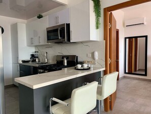 Een moderne keuken met een centraal eiland, roestvrijstalen apparatuur en een marmeren achterwand.