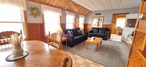 Una sala acogedora con una mesa de comedor de madera, un sofá, una mesa baja y una chimenea.