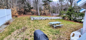 Patio con muro de piedra, una mesa de picnic y una silla blanca.