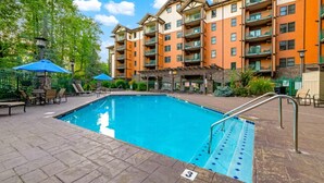 A swimming pool with a lifeguard stand, lounge chairs, and a covered seating area. - Baskins Creek 109 (Gatlinburg)