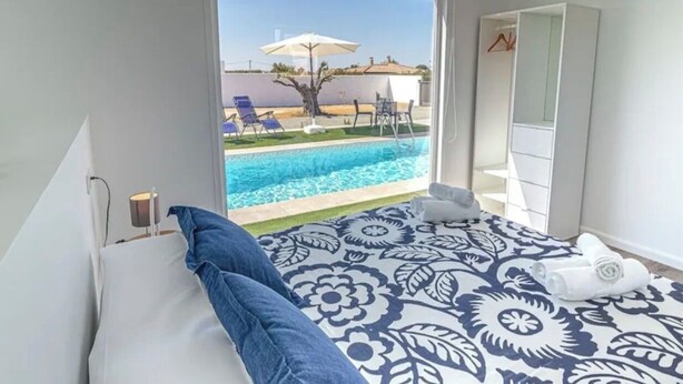 Un dormitorio con cama, vista a una piscina y un armario blanco.