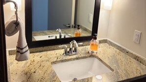 A bathroom with a granite countertop, a white sink, a mirror, and a towel rack. - Cozy 1-bedroom apartment in amazing Downtown Dallas sleeps 4 (Dallas)