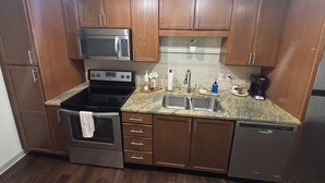 A kitchen with wooden cabinets, a stainless steel microwave, a stove, a sink, and a dishwasher. - Cozy 1-bedroom apartment in amazing Downtown Dallas sleeps 4 (Dallas)