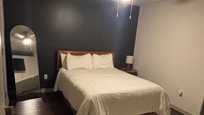 A bedroom with a bed, a ceiling fan, a nightstand, a lamp, and a patterned rug. - Cozy 1-bedroom apartment in amazing Downtown Dallas sleeps 4 (Dallas)