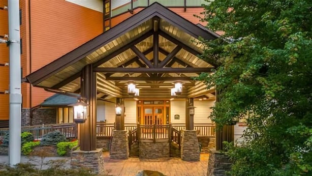 A building with a covered entrance, stone pillars, and a wooden deck. - Baskins Creek 112 (Gatlinburg)