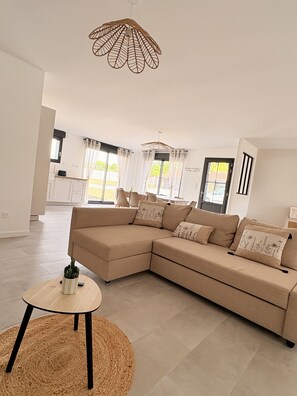 A modern living room with a sectional sofa, a round coffee table, and a unique ceiling light fixture.