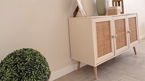 A hallway with a white cabinet, a large wall clock, and a potted plant.