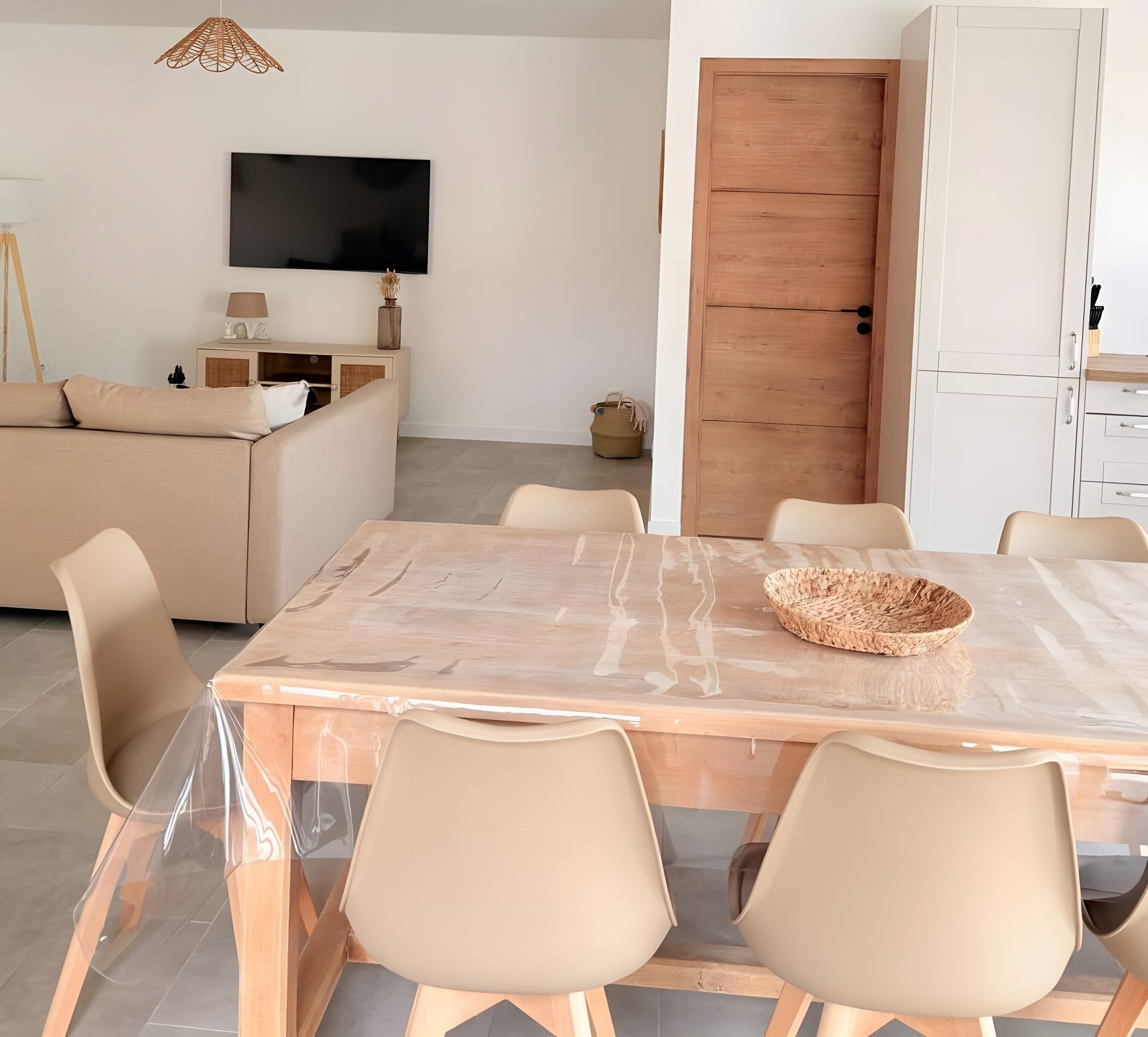Een moderne woonkamer met een bank, een televisie, een eettafel met stoelen en een houten deur.