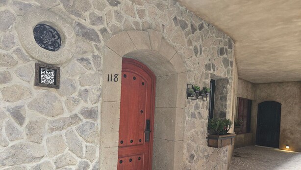 Un edificio in pietra con una porta rossa, un codice QR e un tappetino di benvenuto.