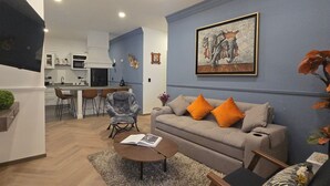 Un soggiorno moderno con un divano grigio, cuscini arancioni, un tavolino da caffè e un quadro appeso al muro.