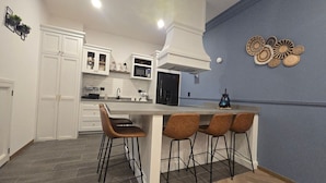 Una cucina moderna con mobili bianchi, un'isola centrale con sgabelli da bar, un forno a microonde e una parete decorata in blu.