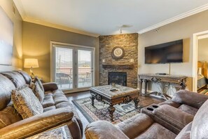 A living room with a stone fireplace, a flat-screen TV, a sofa, and a coffee table. - Baskins Creek 201 (Gatlinburg)