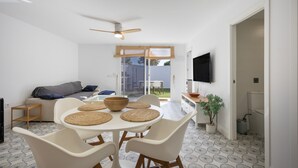 Una cocina moderna con comedor, ventilador de techo, televisor montado en la pared y una planta en maceta.