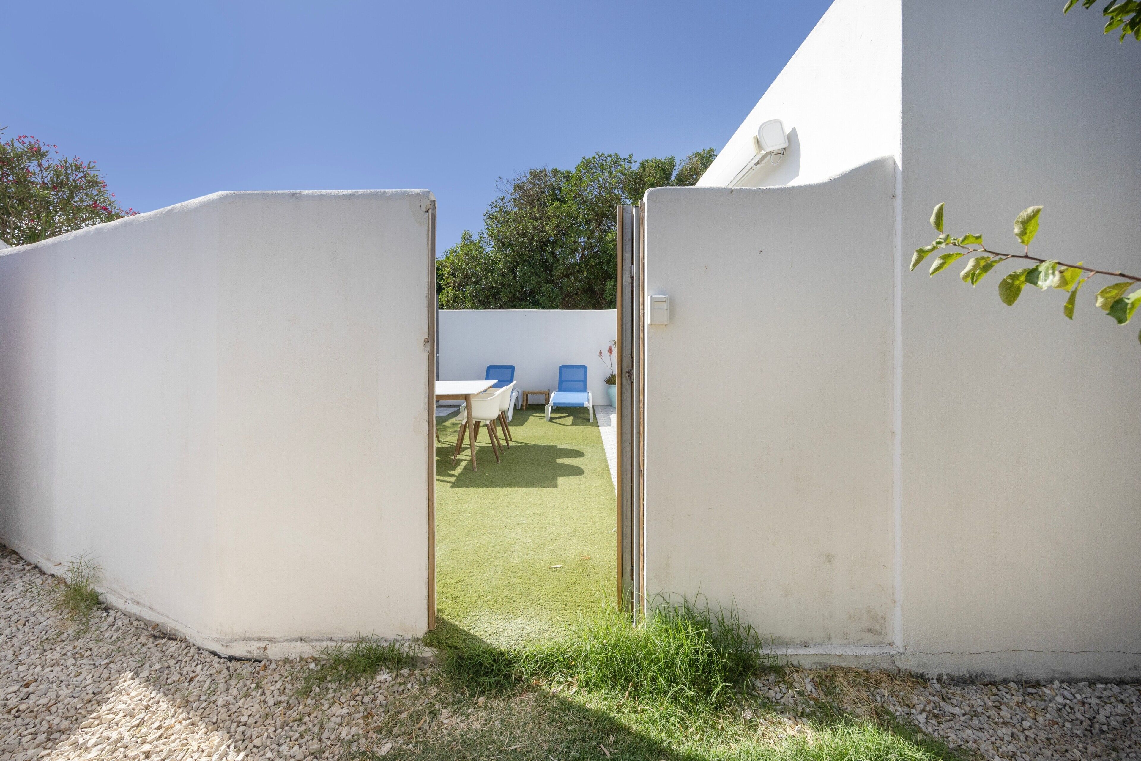 Un edificio bianco con una porta che si apre su un patio con sedie blu e un tavolo.