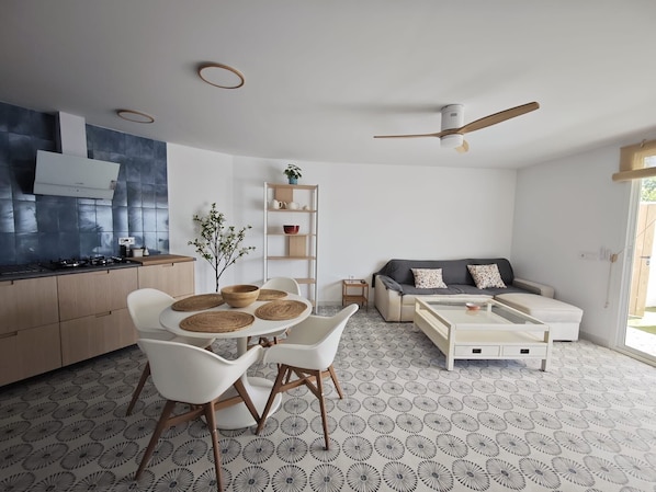Un salon moderne comprenant un canapé, une table basse et un coin repas avec des chaises et une table.