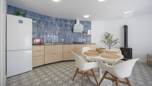 Una cocina moderna con estufa integrada, armarios blancos y un comedor con mesa redonda y sillas blancas.