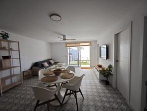 Un salon moderne comprenant un coin repas, un canapé, un téléviseur et un balcon.
