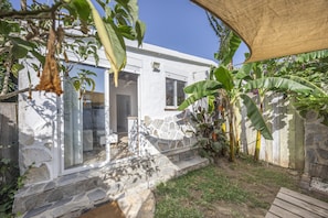 Ein Haus aus Stein mit Glastür, einer Terrasse und einem Holzzaun.