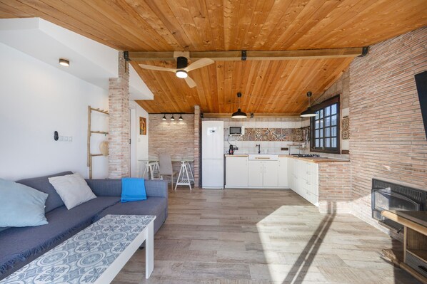 Ein moderner Wohnraum mit Holzbalkendecke, einer Küche mit Ziegelrückwand und einem Kamin.