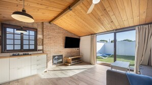 A modern kitchen with a TV, wooden ceiling, and a view to the outside.