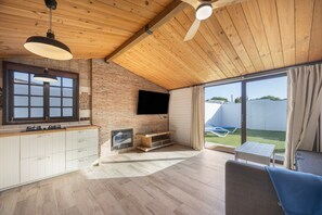 A modern kitchen with a TV, wooden ceiling, and a view to the outside.
