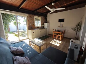A cozy living area with a sofa, a dining table, and a kitchen area with a refrigerator and a TV.