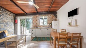 Una cucina con parete in pietra, soffitto in legno e zona pranzo con tavolo e sedie.