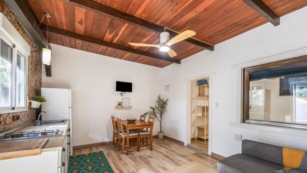 Una cucina compatta con zona pranzo, ventilatore a soffitto e divano.