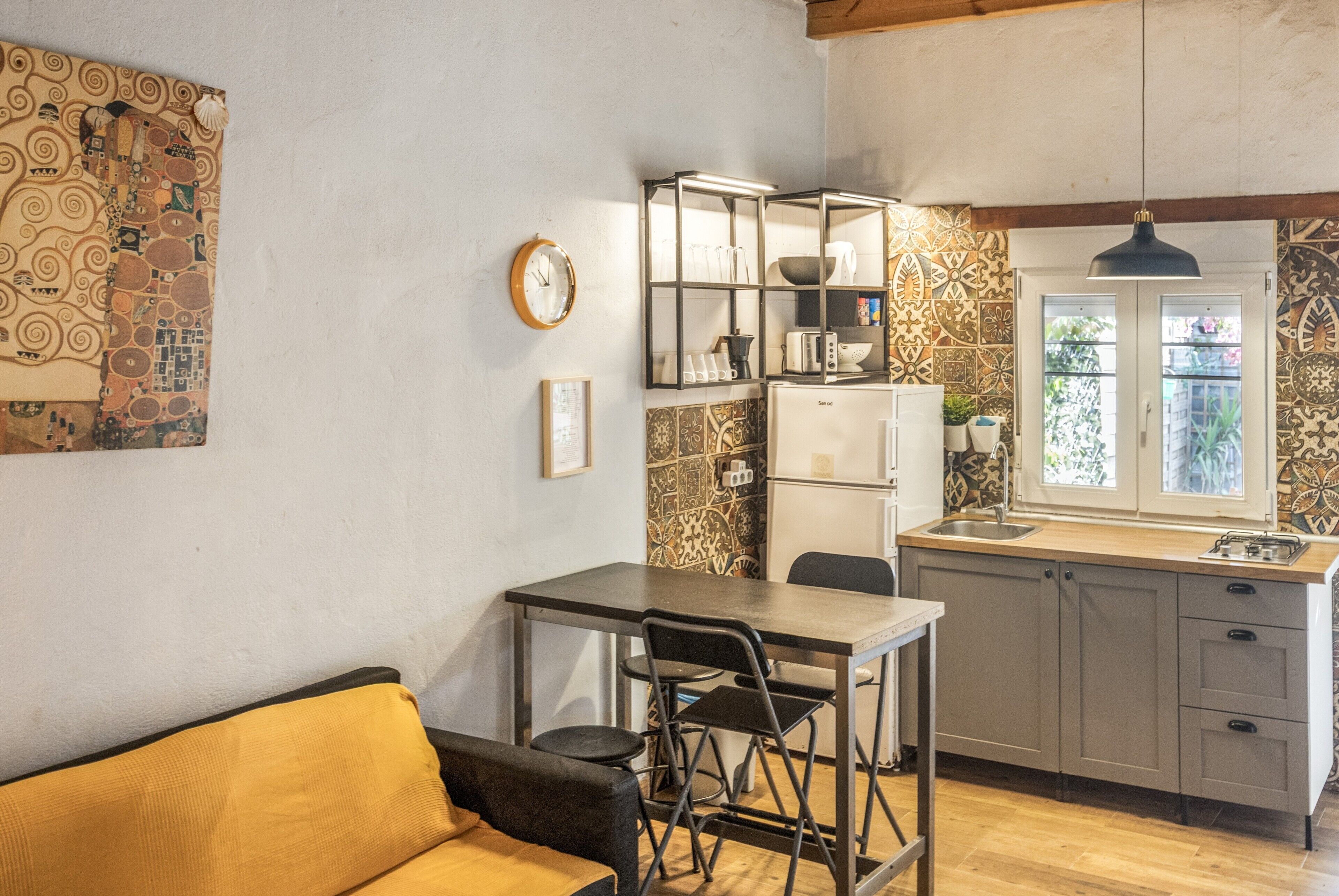 Cocina compacta con comedor, refrigerador y ventana con vistas.
