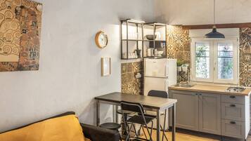 Cocina compacta con comedor, refrigerador y ventana con vistas.