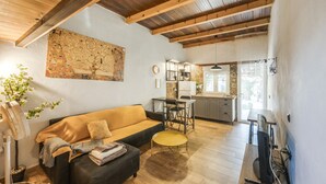A cozy living area with a sofa, a small round table, a fan, and a TV. - Casa Pequeña Lulú - Sunwaves, just 5 minutes’ walk from the beach (El Palmar de Vejer)