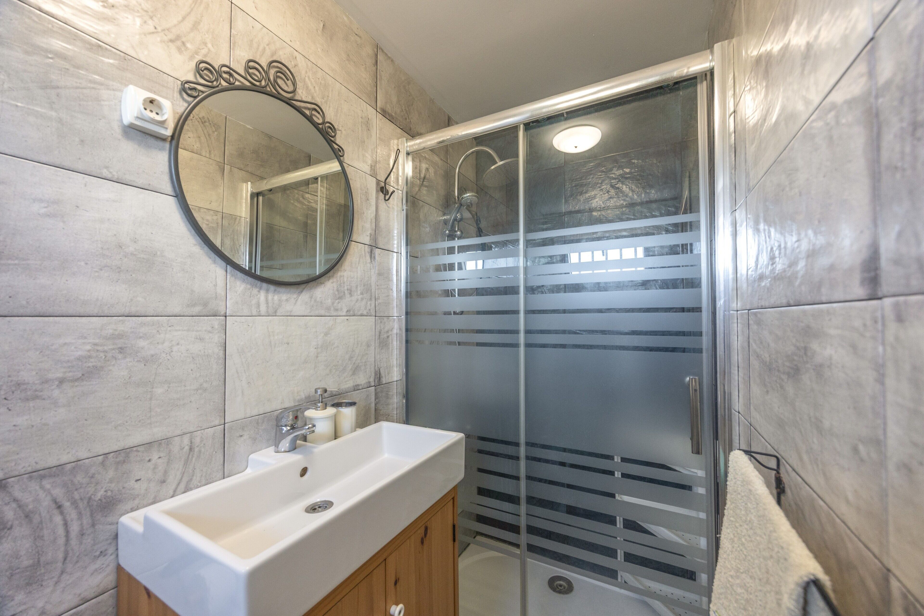 Une salle de bain équipée d’un lavabo, d’un miroir et d’une cabine de douche.