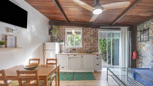 Une cuisine avec un plafond en bois, un téléviseur fixé au mur, une table à manger avec des chaises et un pare-feu décoratif.