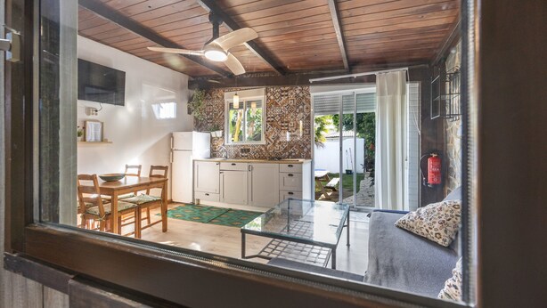 Une cuisine moderne avec un plafond en bois, un coin repas avec une table et des chaises, et un salon avec un canapé.