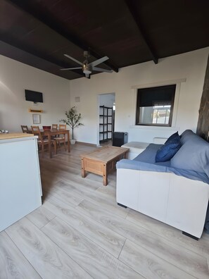Um espaço de estar moderno com uma mesa de jantar de madeira, um sofá, uma mesa de centro e um ventilador de teto.
