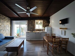 Una cocina moderna con protector contra salpicaduras de piedra, una zona de comedor con muebles de madera y un ventilador de techo.