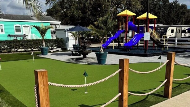 A playground with a slide and climbing structures, surrounded by a rope barrier and greenery. - Family-Friendly Cottage Near Disney with Pool, Playground & Resort Amenities (Kissimmee)