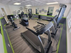 Ein Fitnessstudio mit Laufbändern, Crosstrainern und Gewichten.