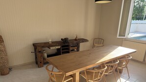 Een eetruimte met een houten tafel en stoelen, een rustieke houten bureau en een raam met uitzicht.