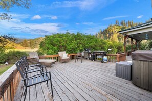 Una terraza de madera con mobiliario exterior, un jacuzzi y una zona de barbacoa.
