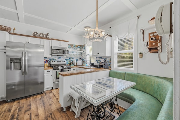 A kitchen with stainless steel appliances, a central island, and a green upholstered bench.