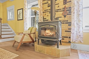 A room with a fireplace, a chair, a staircase, and a window.