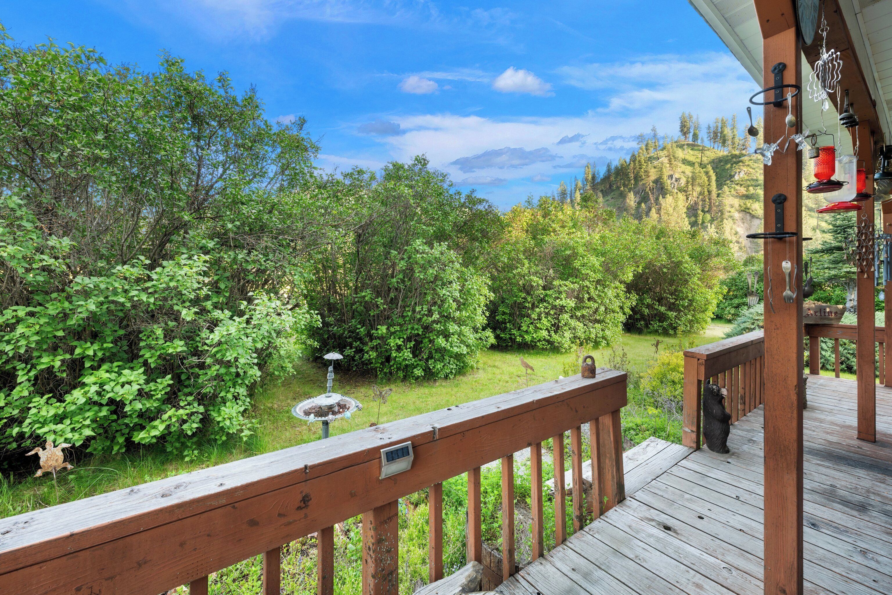 A wooden deck with a view of a lush garden and a mountain in the background.