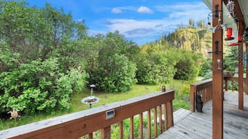A wooden deck with a view of a lush garden and a mountain in the background.