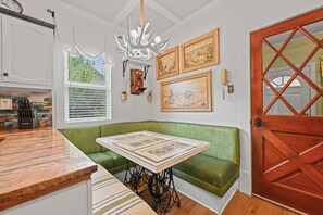 Una cocina con un banco verde, una puerta de madera y una araña.