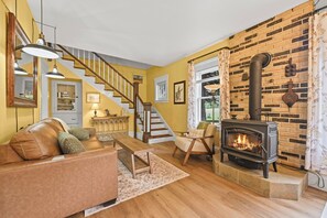 Una sala de estar con chimenea, una escalera y un sofá.