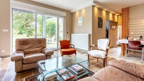 A spacious living area with a glass coffee table, leather sofas, and a dining table with chairs. - Bed and Breakfast 'Une Chambre À Lestriguiou' with Private Terrace, Private Garden and Wi-Fi (Plomeur)